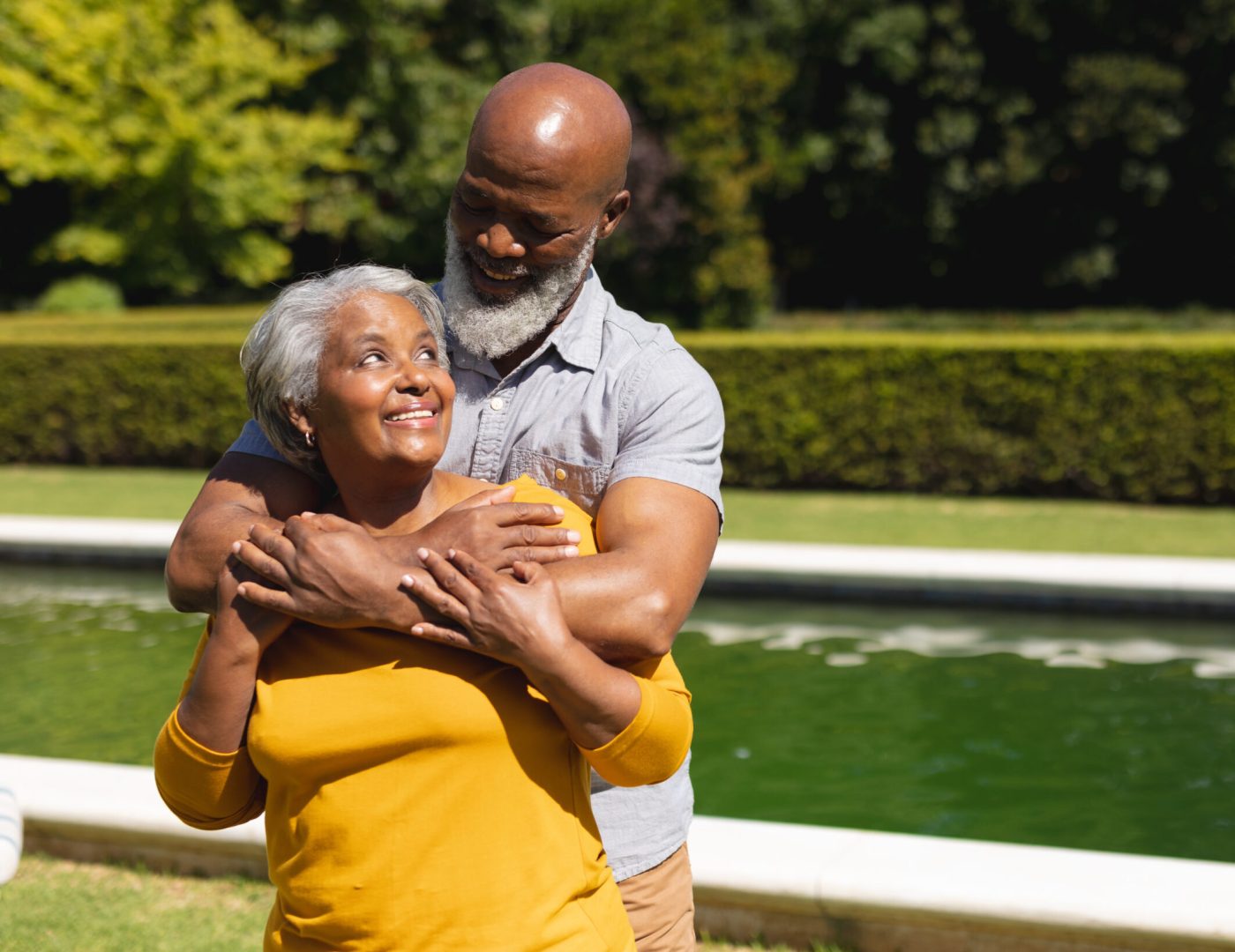 Senior african american couple spending time in sunny garden together embracing and smiling